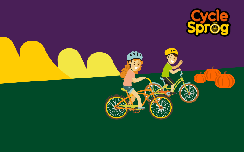 A cartoon graphic of two children riding bikes on a grassy hill with pumpkins and the Cycle Sprog logo