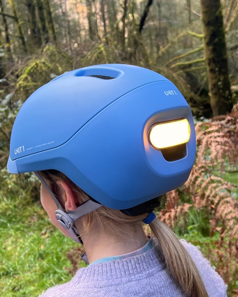 A girl wearing a blue SPARKY helmet- with the red rear bike light